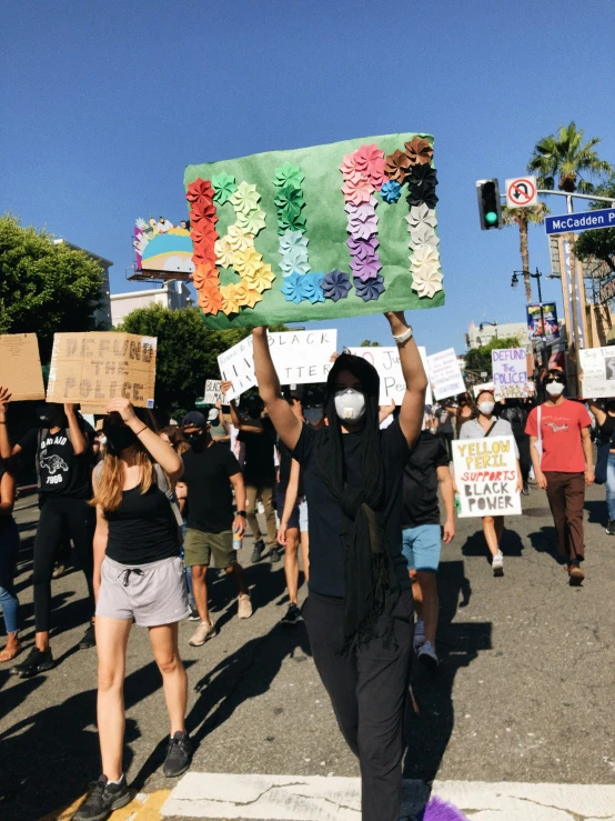 a crowd of people holding signs and wearing face masks