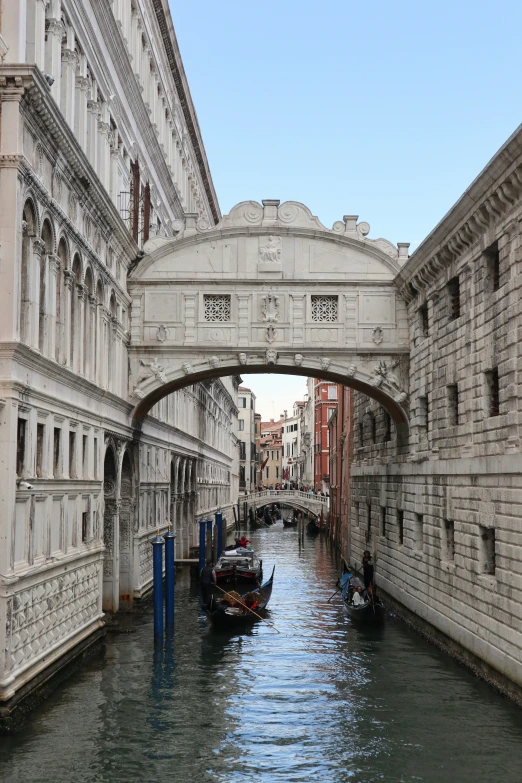 boats go under a bridge in a canal in venice
