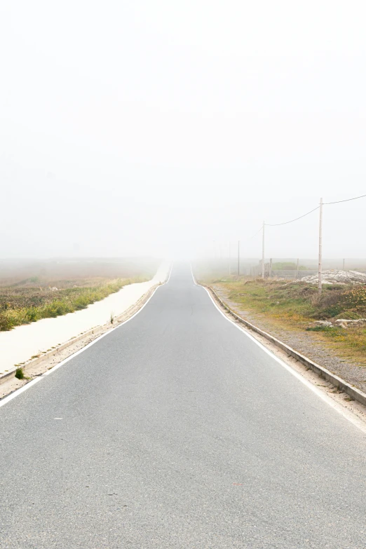 an empty road going into the distance, in between two grassy plains