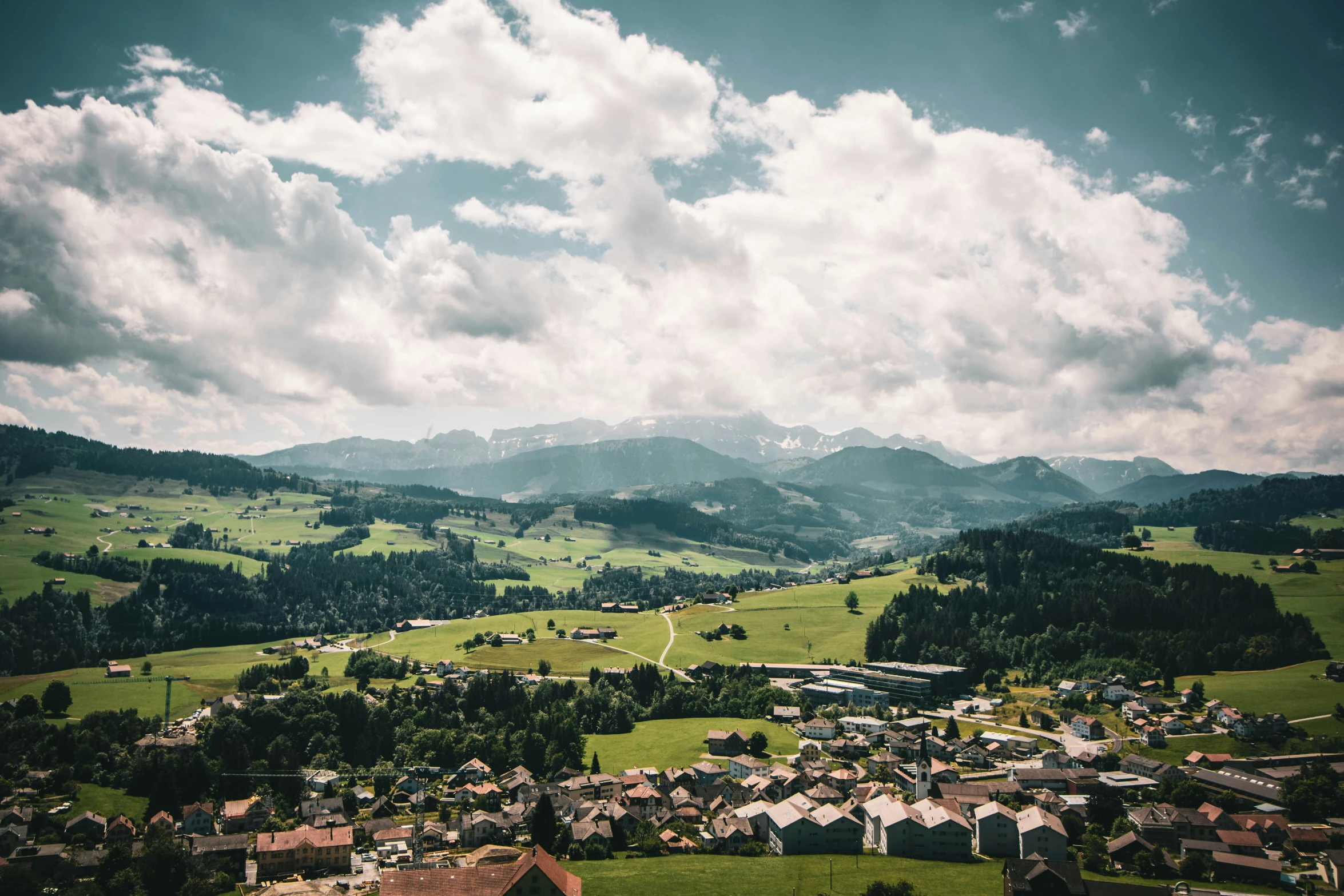 an aerial view of green rolling hills and houses