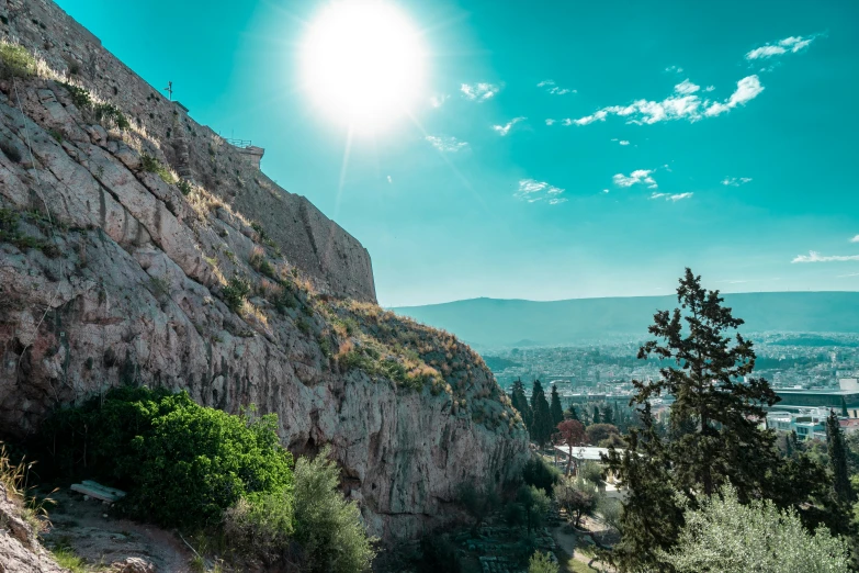 a sun shining down on a rocky mountain with trees around