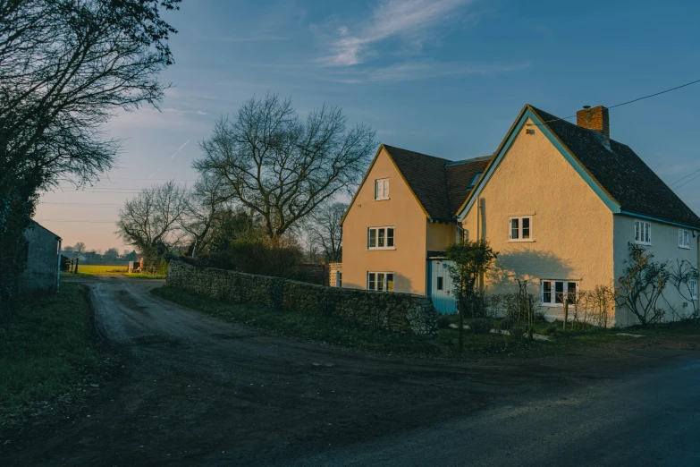 a yellow house is shown on a dirt road