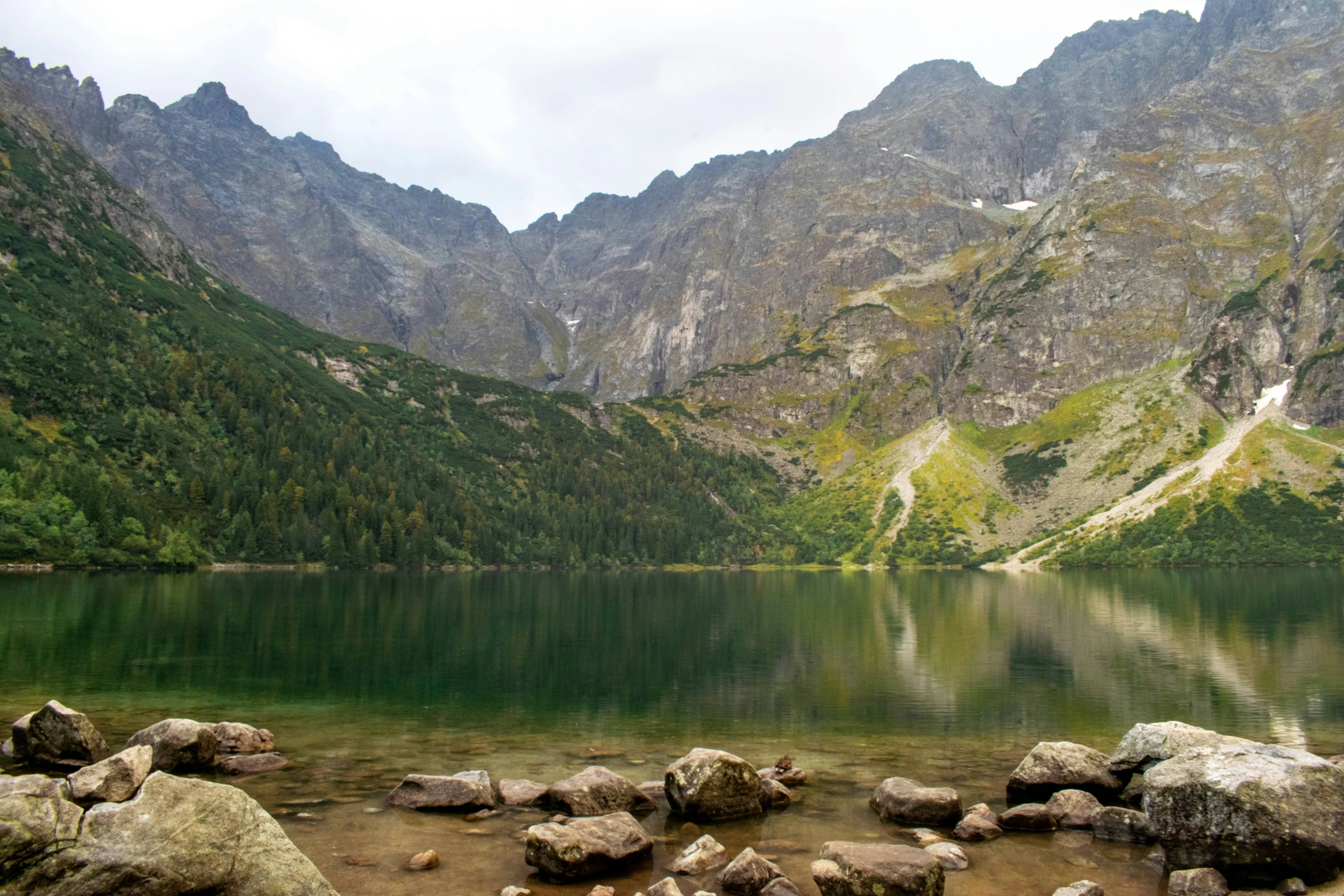 a lake surrounded by mountains and boulders next to it