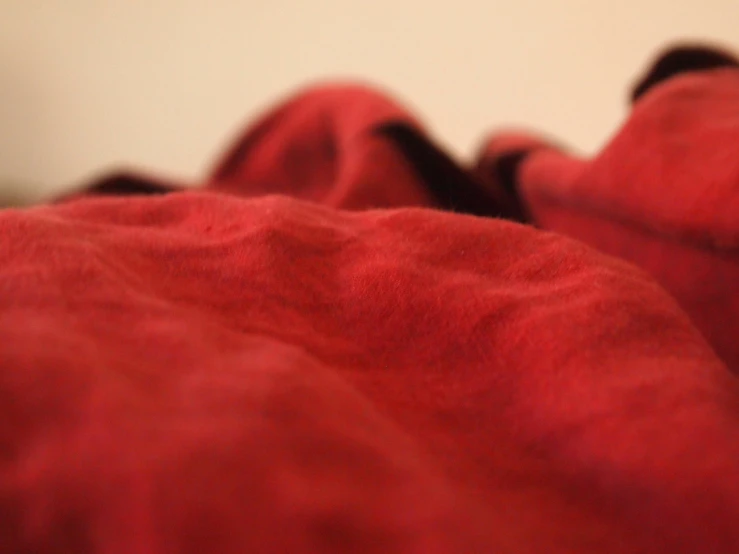 red blanket in bed with a white wall