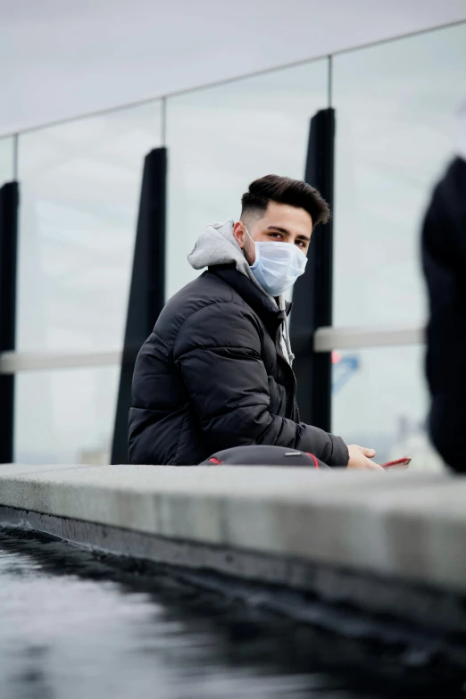 a man in grey and black jacket sitting on a sidewalk