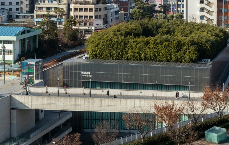 a long bridge over a street with a building on one side and a cityscape on the other