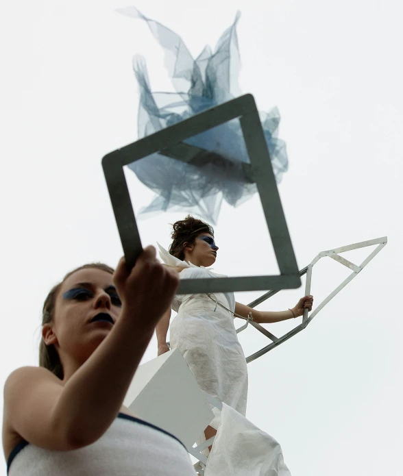 a woman standing under an artistic structure holding up a po