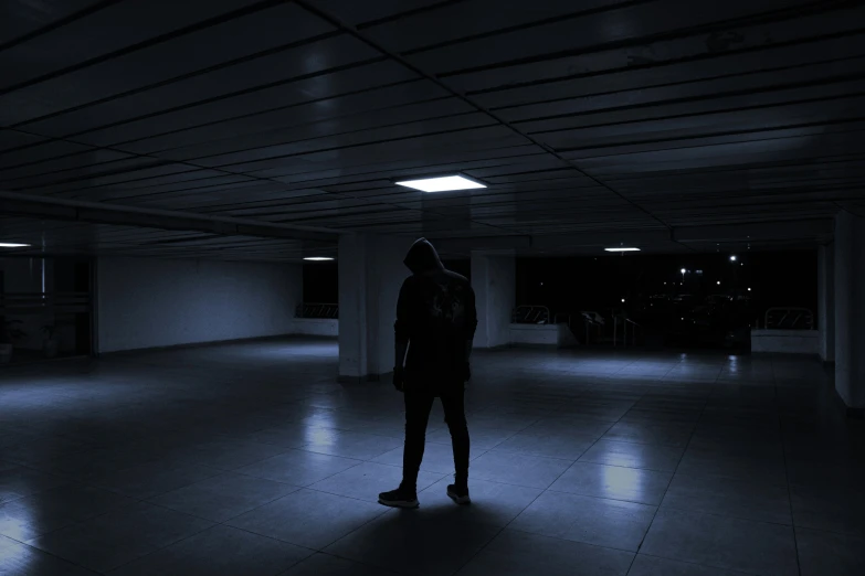 a man in dark room with dark lighting coming from ceiling