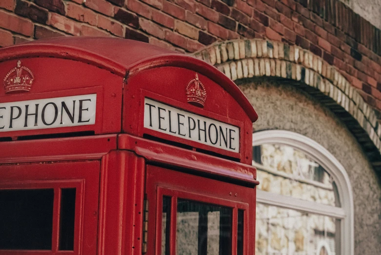 a red phone booth sitting on top of a brick building