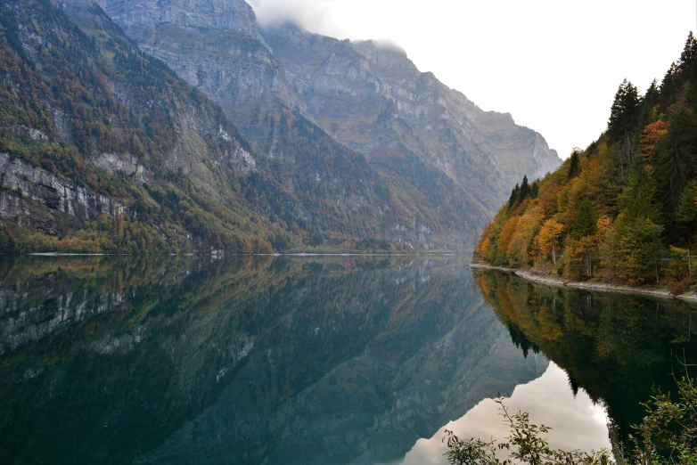 a body of water surrounded by mountains with a few clouds