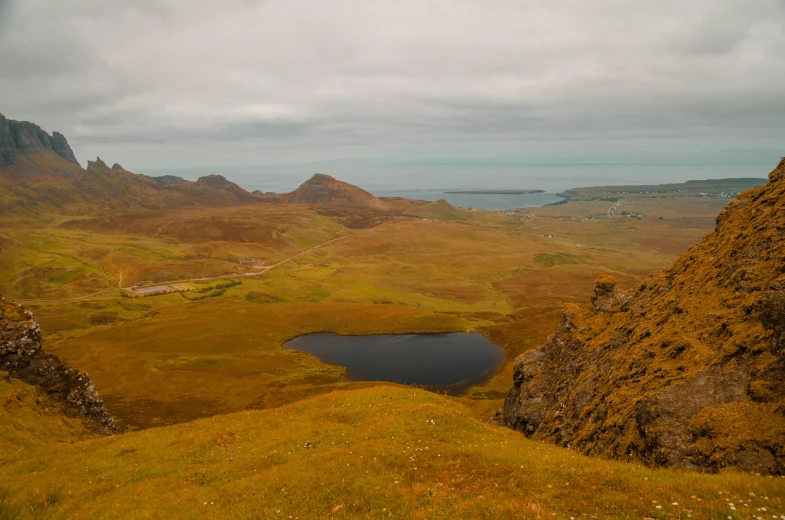 a cloudy sky hangs over the landscape, and there is water and grass