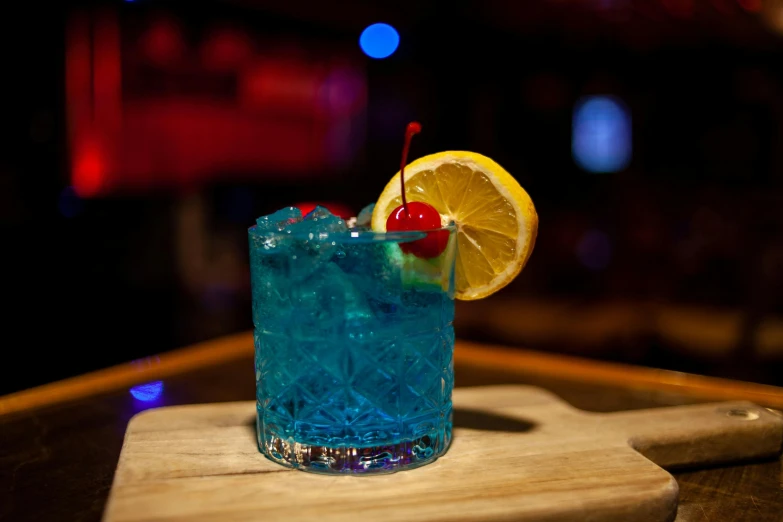 the blue cocktail has a cherry and lime on it