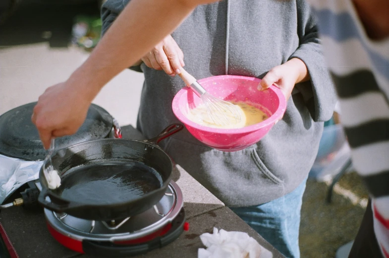 a person cooking soing outside in a pink bowl