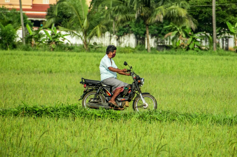 a man riding on the back of a motorcycle down a grass covered field