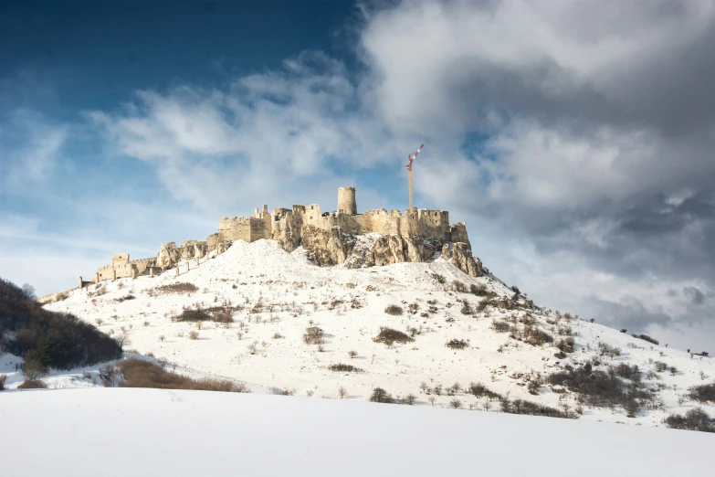 the winter scenery of a mountain range with a castle on top