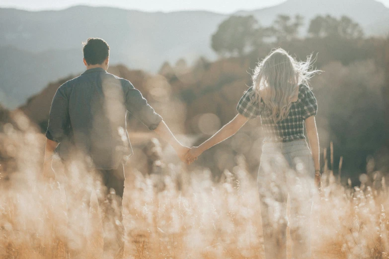 a couple holds hands as they hold hands in an open field