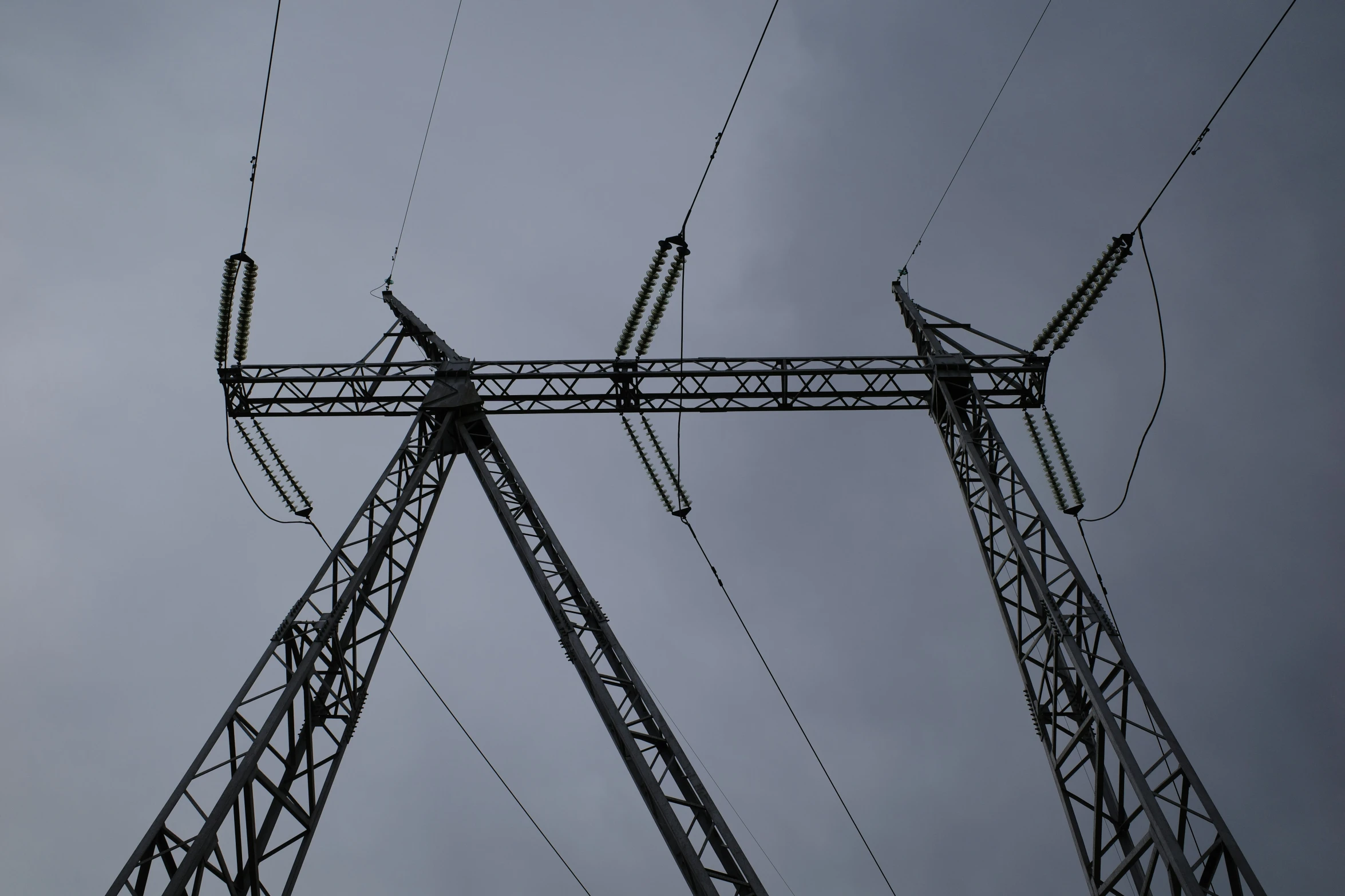 the top of power lines and wires against a cloudy sky