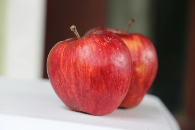 two red apples sitting next to each other