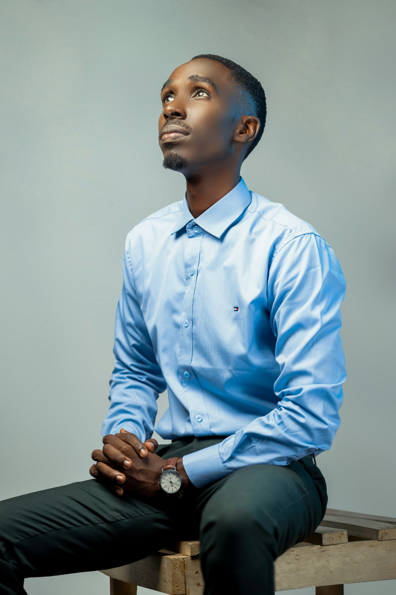 a man in a blue shirt sits on a stool