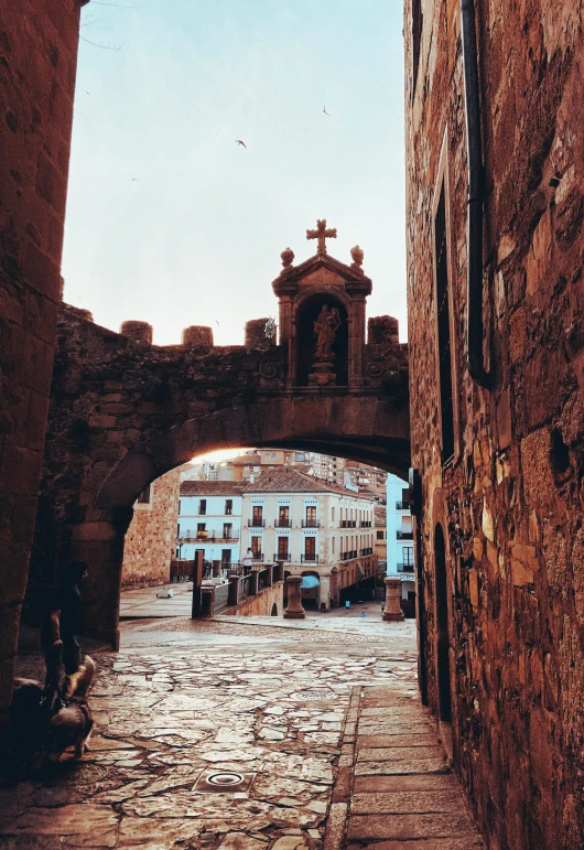 a very old and worn stone alleyway with a cross on top