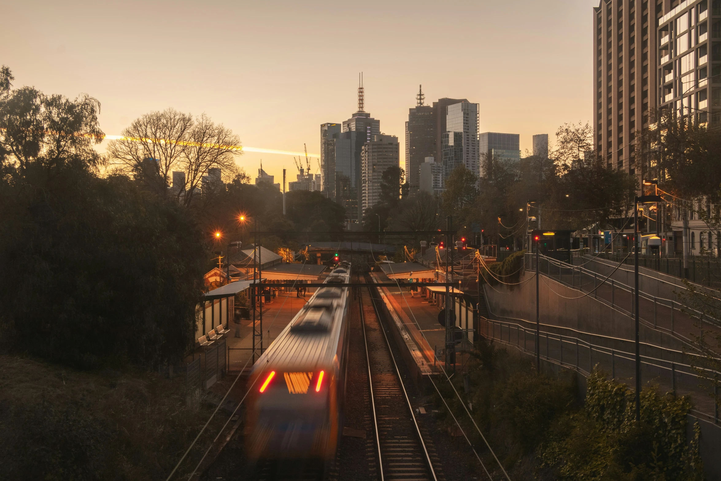 a long white train traveling past a tall building