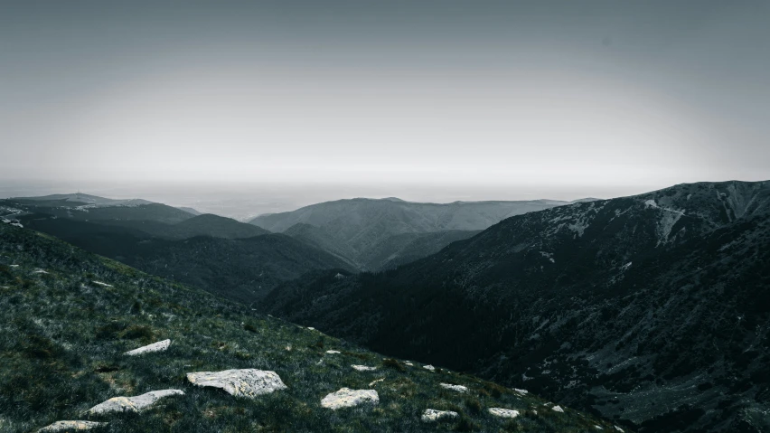 mountain tops and grass with dark clouds above