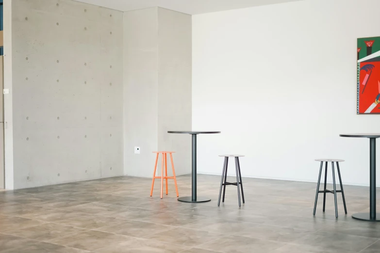 a room with tables and stools and a painting on the wall