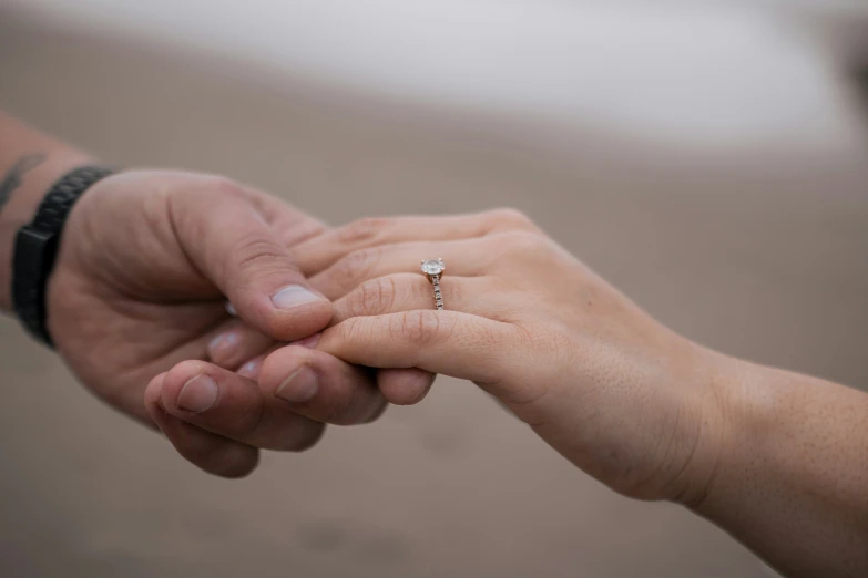 a woman holding the hand of a man with a ring on his finger