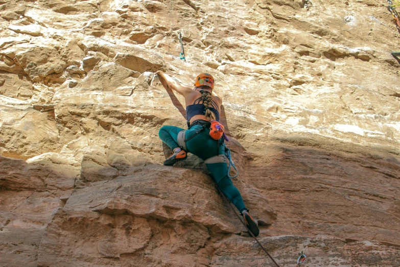 a person sitting on top of a cliff holding onto a rope