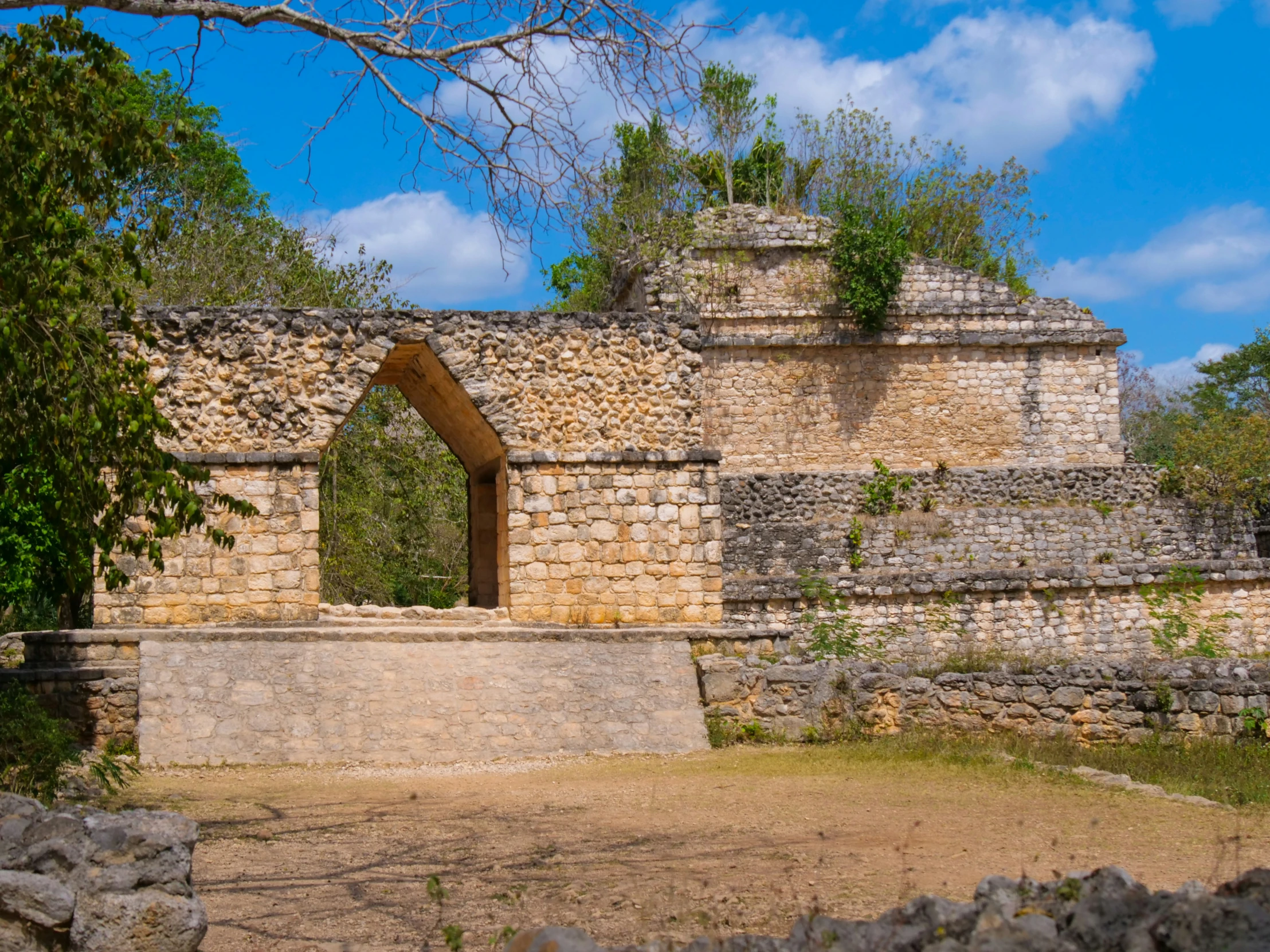 a stone structure sits near some trees and rocks