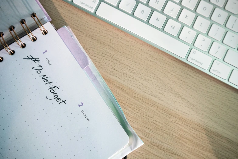 a notepad with writing on it is beside a keyboard