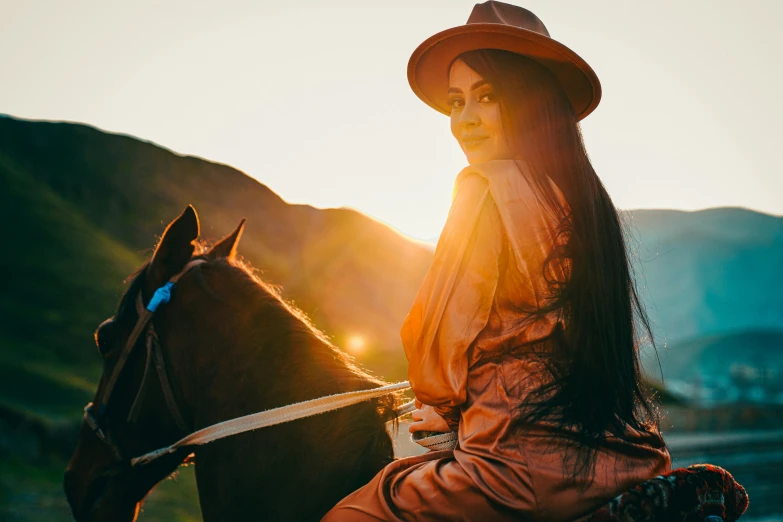 woman in dress sitting on a brown horse during sunset