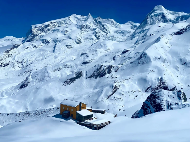 a house and mountains covered with snow during the day