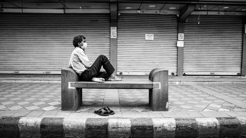 a man is sitting on a bench waiting for his bus