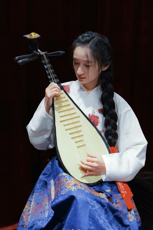 an asian girl playing a harp with a black pole