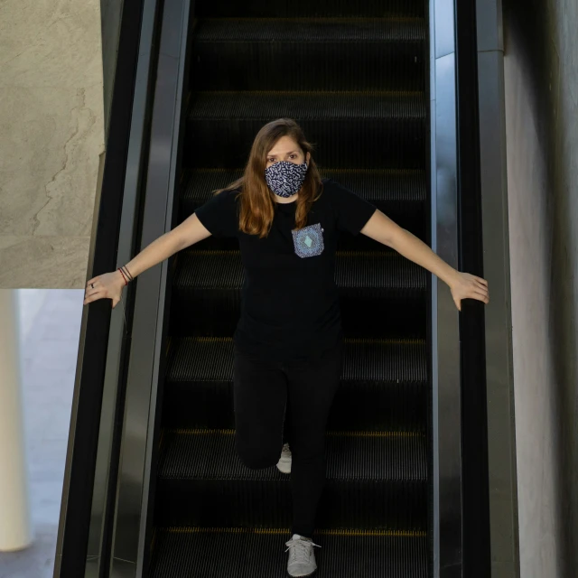 a person with a mask on riding up an escalator