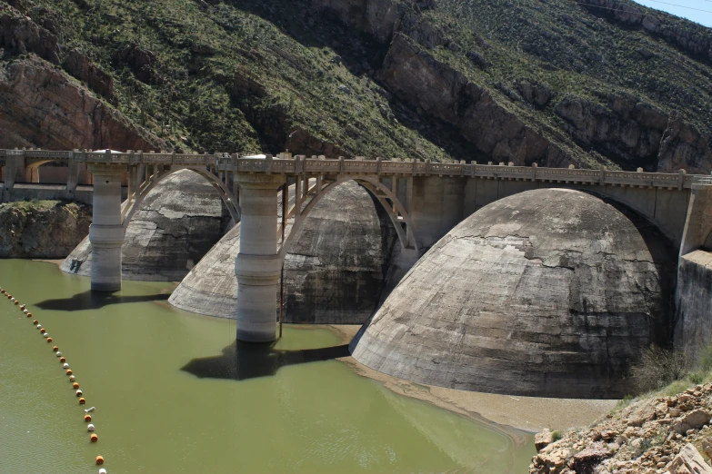 a large stone bridge spanning over water below a mountain