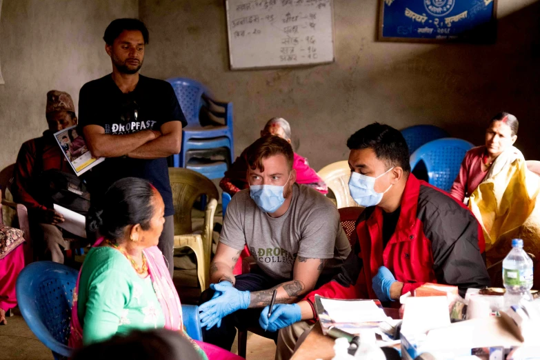 a group of people sitting around each other wearing face masks