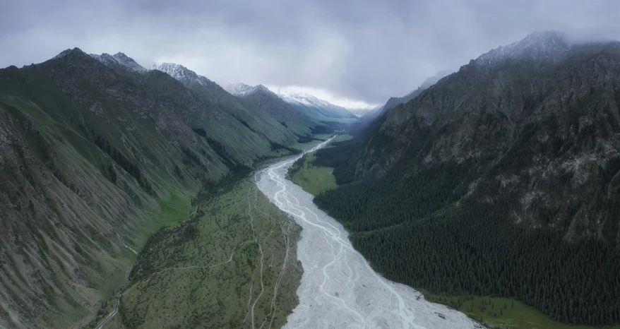 this is the view looking down on a river running through a green mountain valley