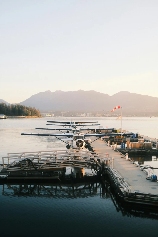 several water planes parked next to a pier on the water