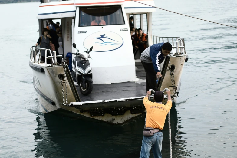 two men are attaching a passenger on the boat