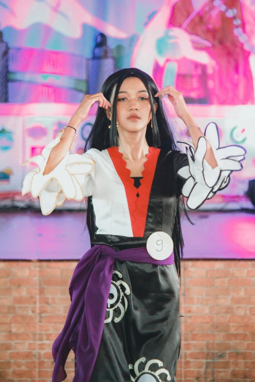 a woman wearing black and white clothing with her hands up