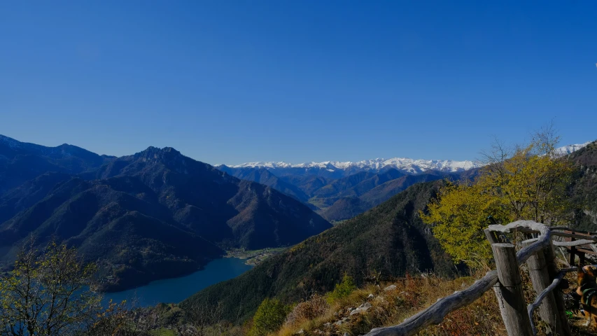 a fence on the side of a mountain with snow capped mountains in the background