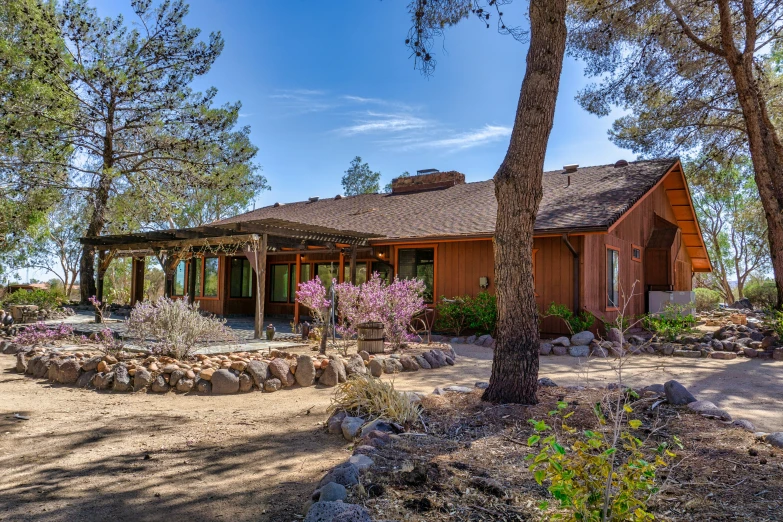 a house sits among trees and rocks under a clear sky