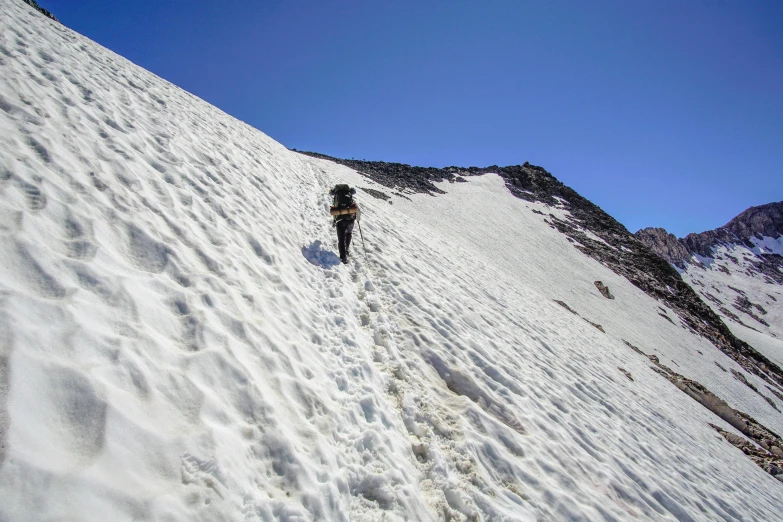 the hiker is climbing up the side of the snow covered mountain