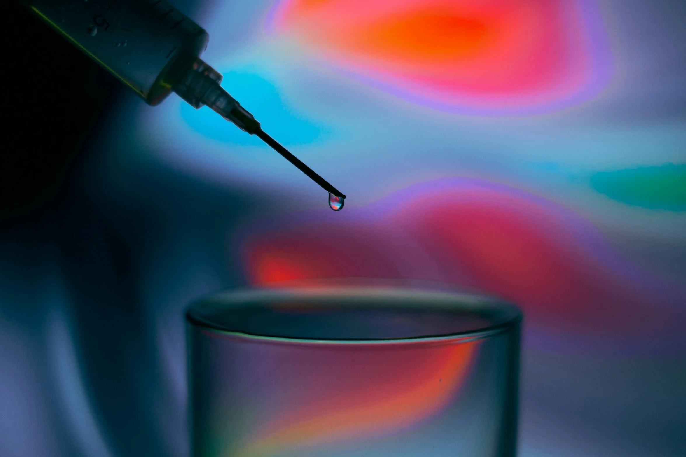 an iv drips out of the tip of a small glass with light background