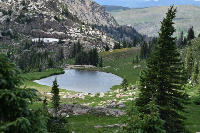 a small lake in the middle of a field and mountains