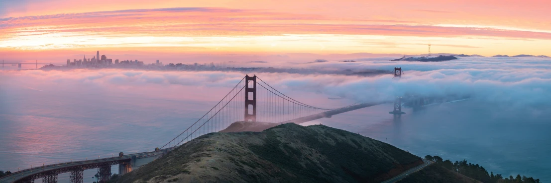 a bridge on top of a hill with the city in the background