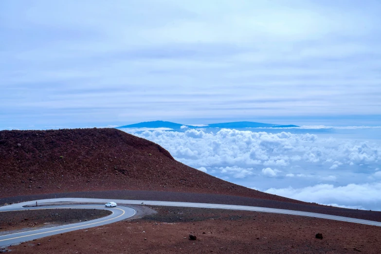 a view of an open mountain, with clouds and mountains below