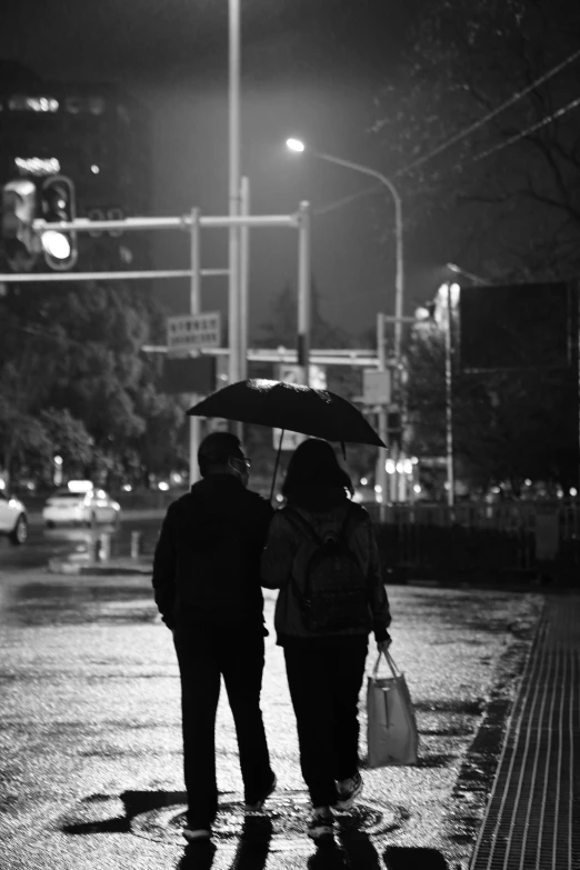 two people are walking down the street holding umbrellas